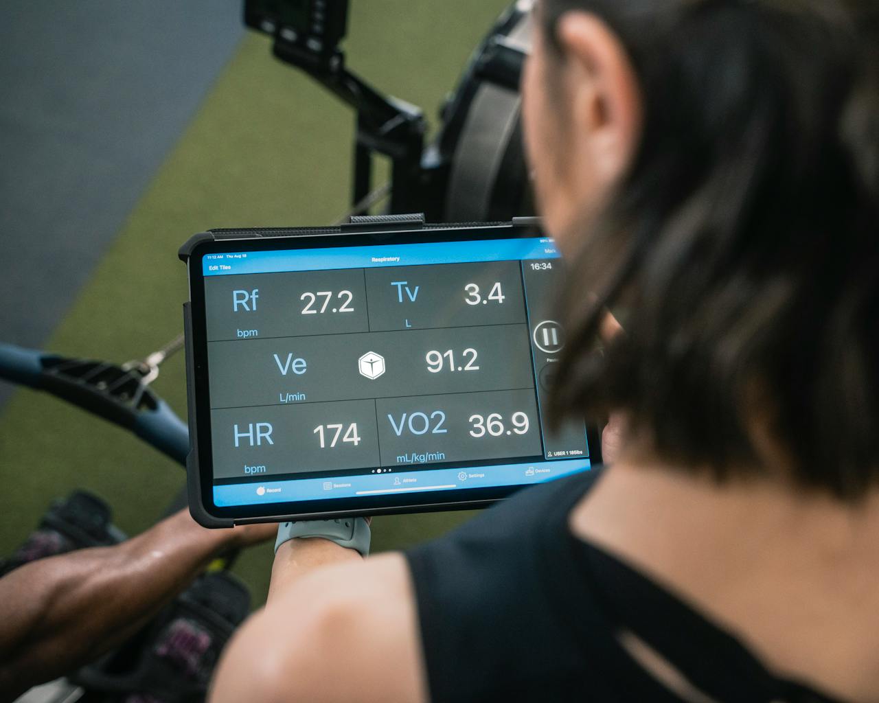 about-01 Adult man reviewing fitness metrics on a tablet during a workout session at the gym.